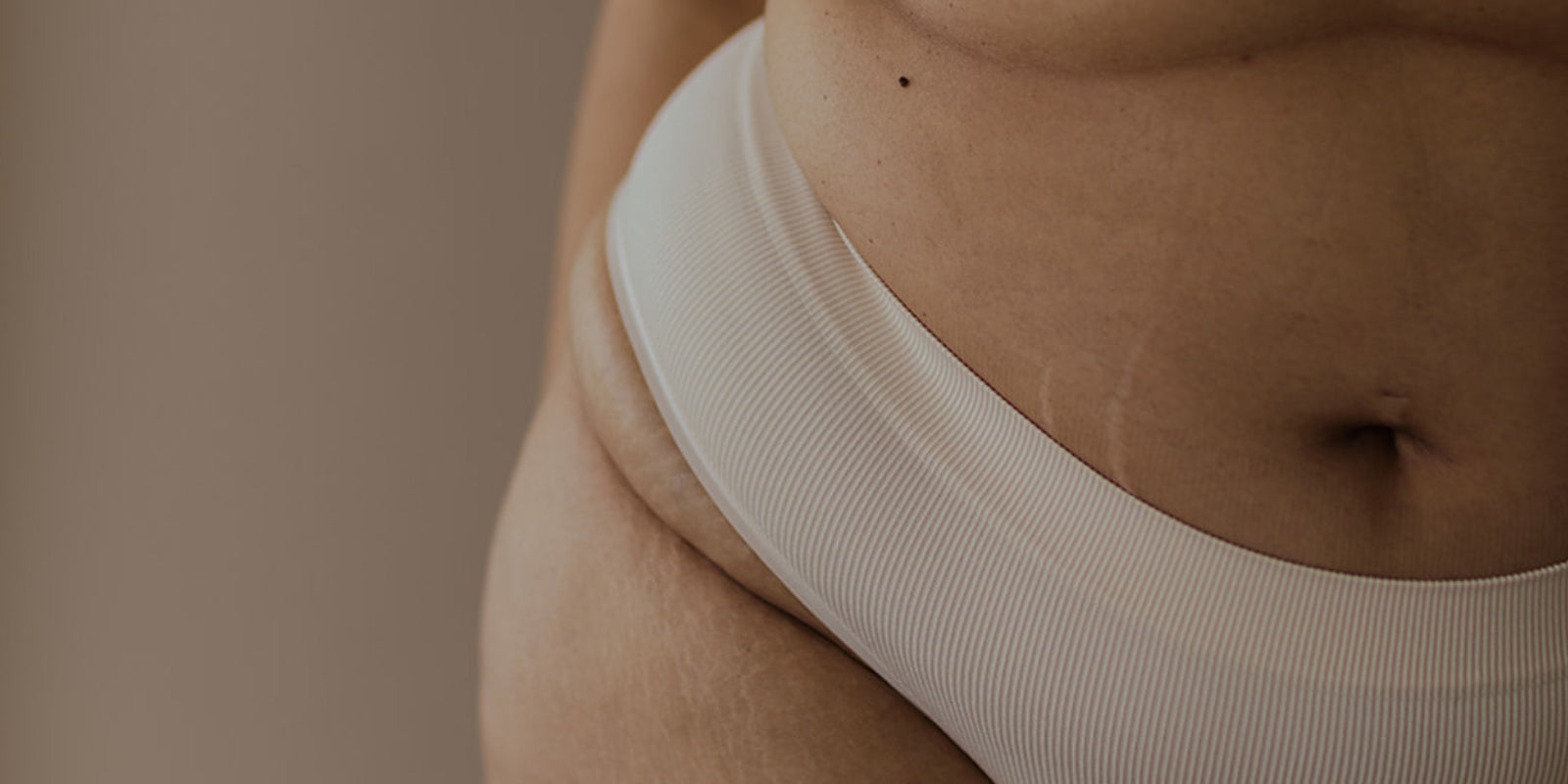 Close-up of a person wearing a beige bra against a neutral background