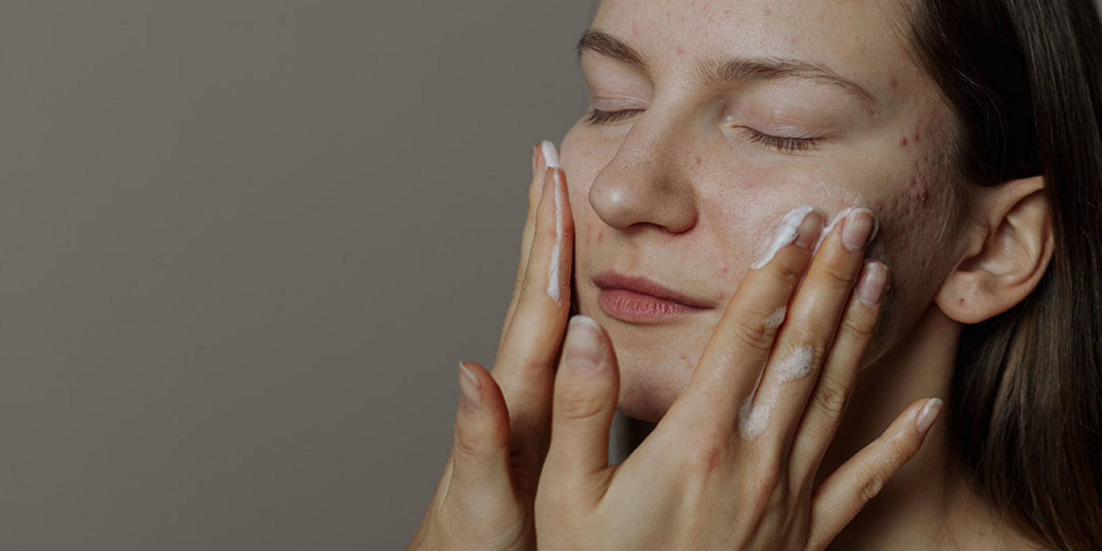 Woman with hands on face against a neutral background